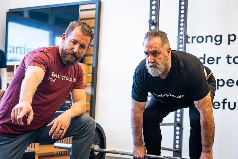 Member of a Starting Strength Gym being coached on the deadlift