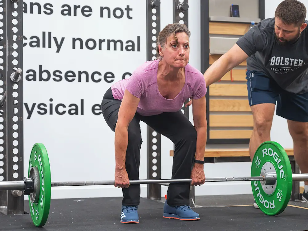 Starting Strength coach correcting deadlift form for female trainee
