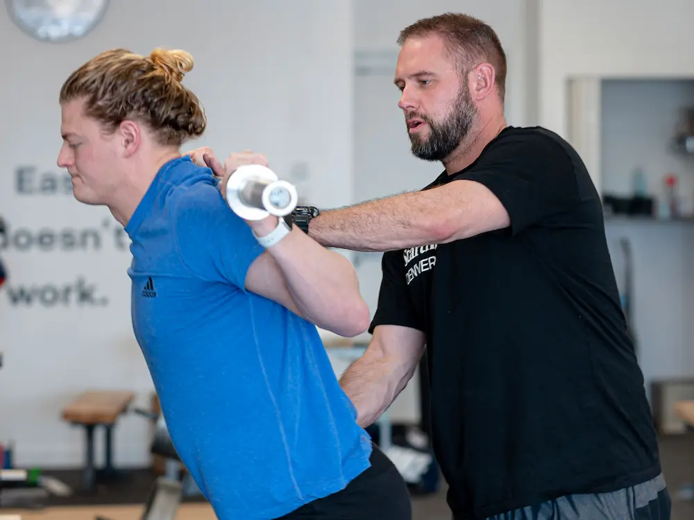 Male coach in Starting Strength Denver shirt teaching press technique