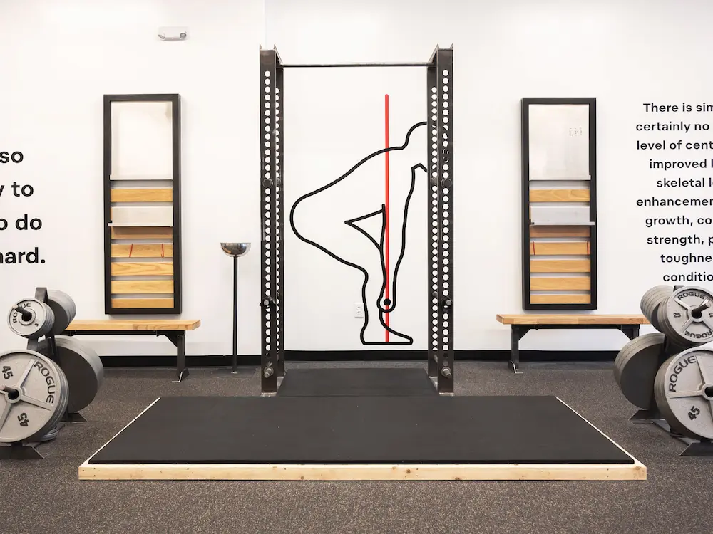 Starting Strength power rack with wall decals and motivational text