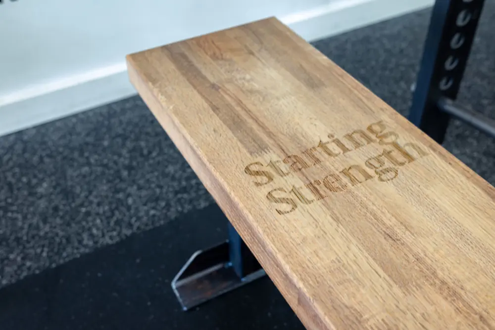Close-up of Starting Strength branded wooden bench engraved with logo