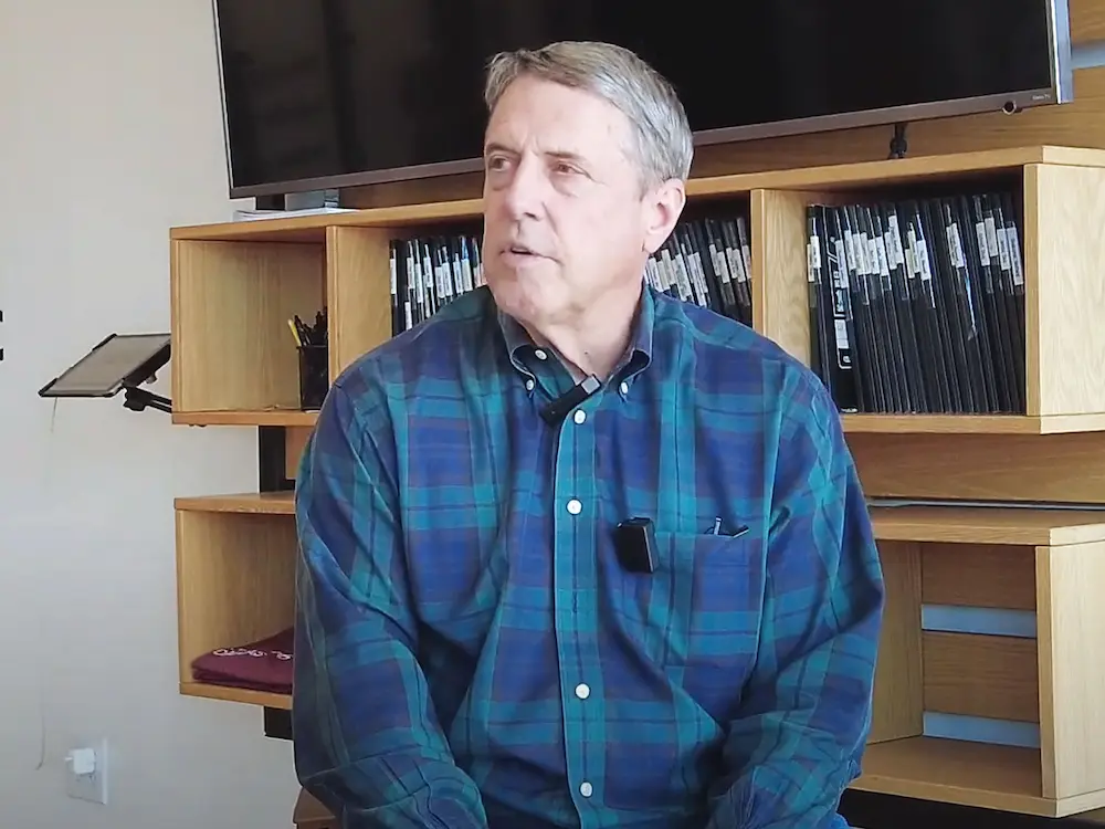 Man in plaid shirt seated at Starting Strength gym office area