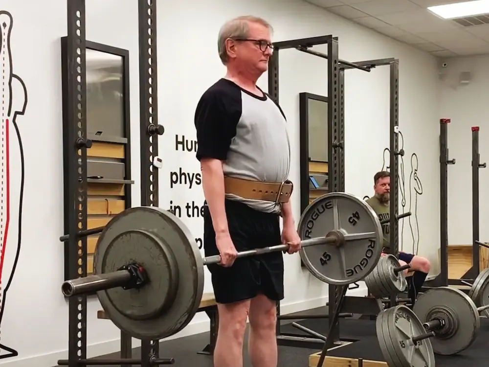 Older male athlete Ken performing deadlift with lifting belt