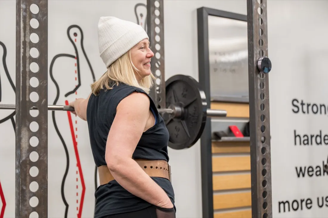 A member smiles with a barbell across her back at Starting Strength Oklahoma City